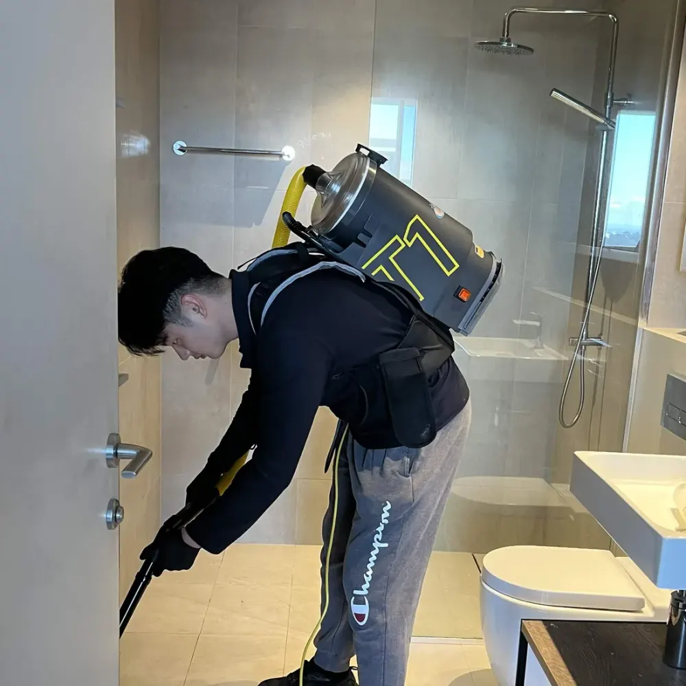 Justin vacuuming a bathroom with a HEPA backpack vacuum